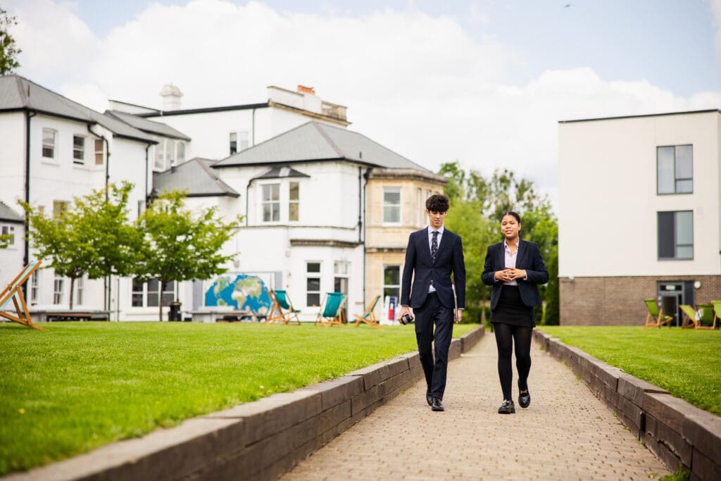 Image of 2 sixth form pupils walking through the school grounds