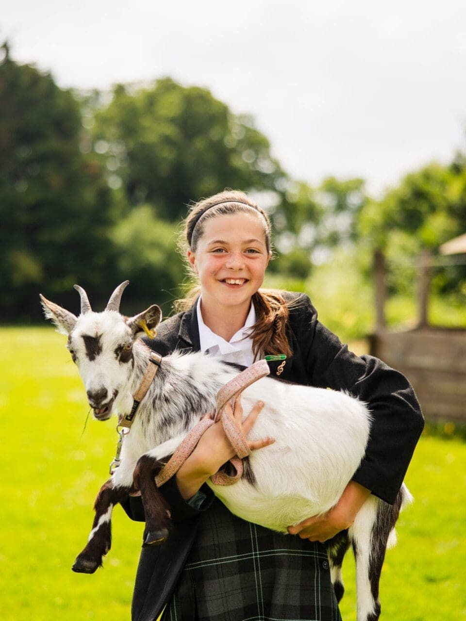 Image of a female pupil carrying one of the school goats